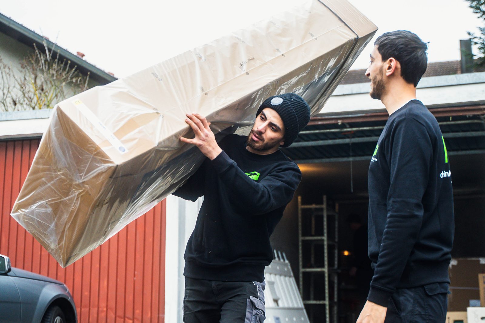 deinMove-Umzugsteam trägt sorgfältig verpackte Möbel beim Privatumzug in Ulm